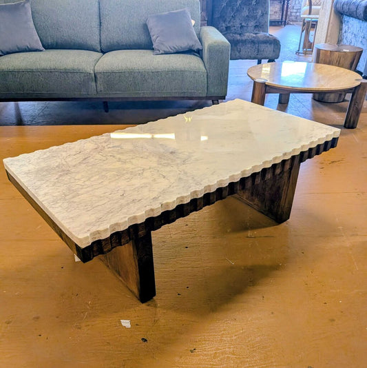 Coffee table with marble top and wooden base in a living room setting