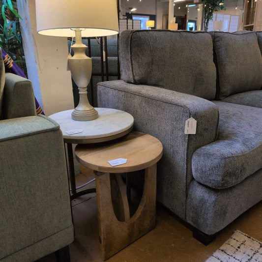 Gray sofa with a lamp and small wooden table in a showroom setting