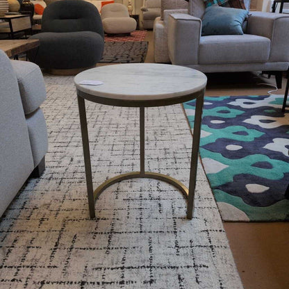 Round side table in a living room setting with furniture and rug.