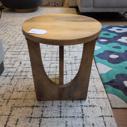 Wooden side table on a patterned rug with a colorful rug partially visible