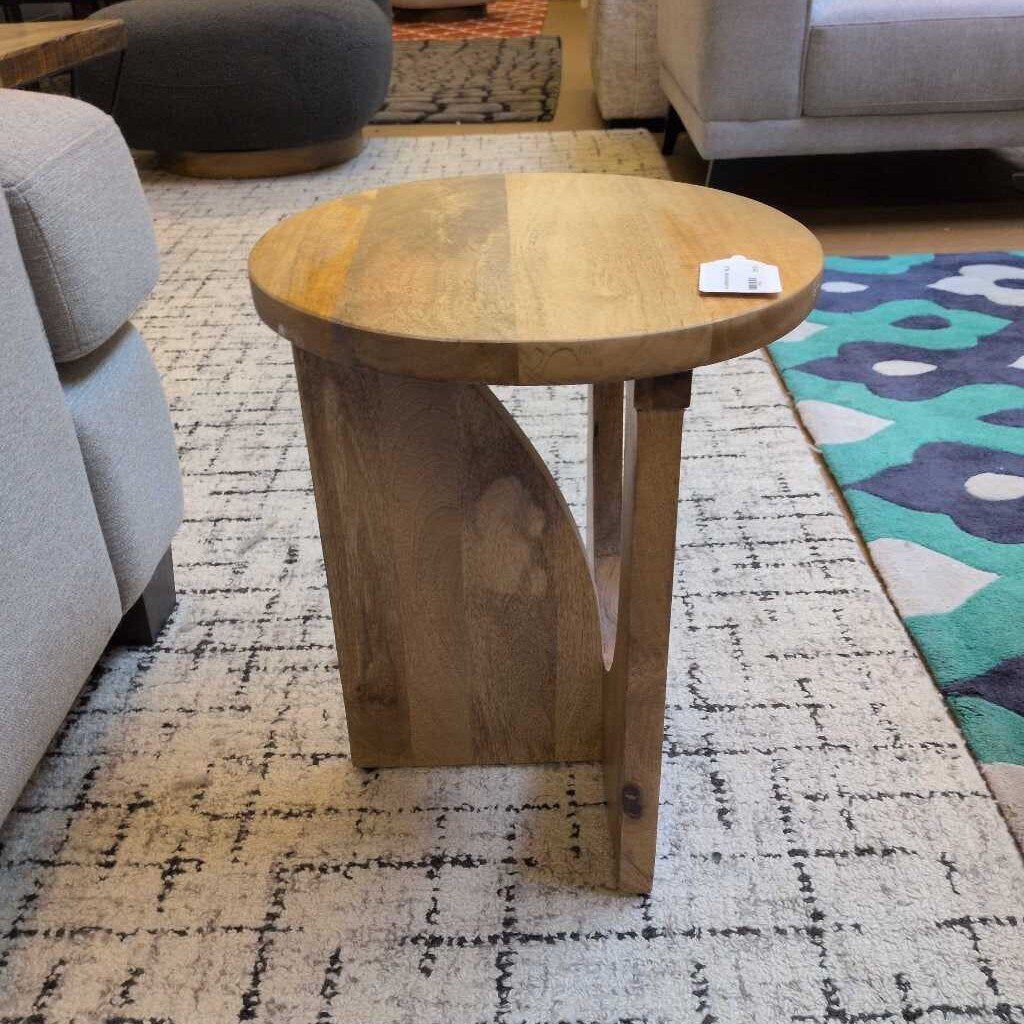 Wooden side table in a living room setting with a rug and sofa.
