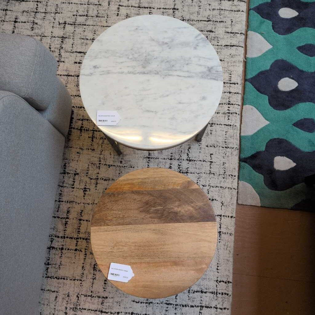 Two round marble and wooden tables on a patterned rug with a floral rug in the corner.