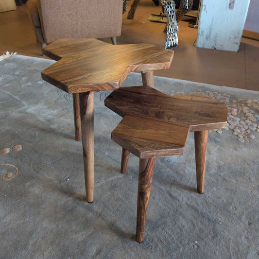 Two wooden side tables on a concrete floor with a chair in the background.