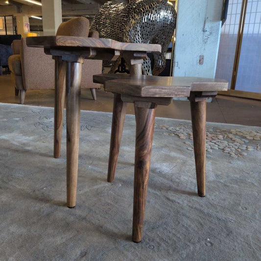 Two wooden tables with twisted legs on a textured floor.