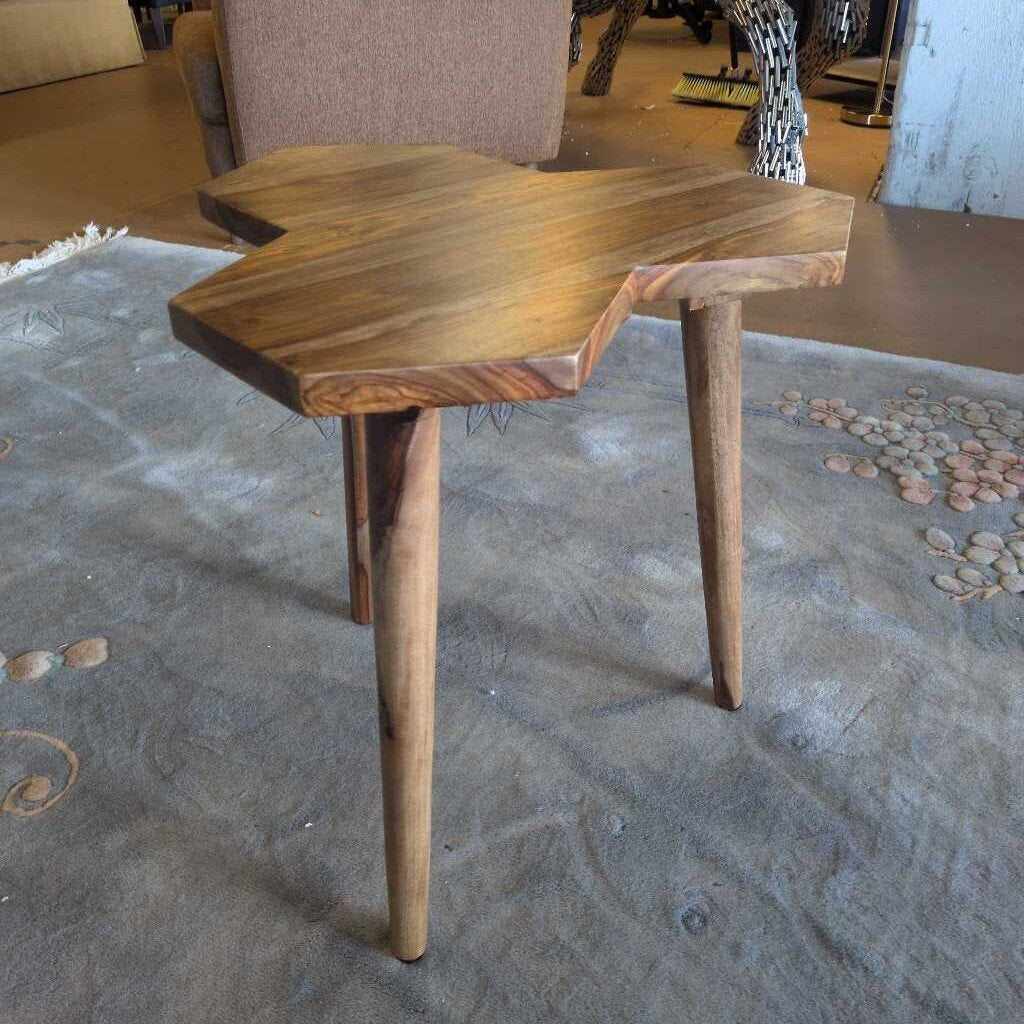 Wooden side table with a natural finish on a textured floor