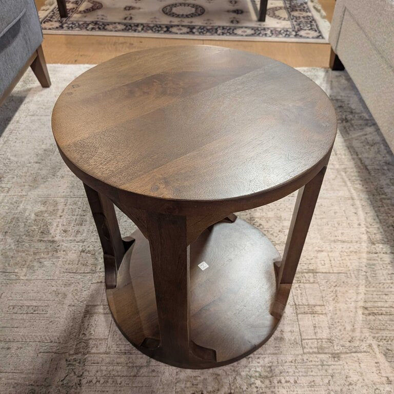 Round wooden side table in a room with a rug and furniture.