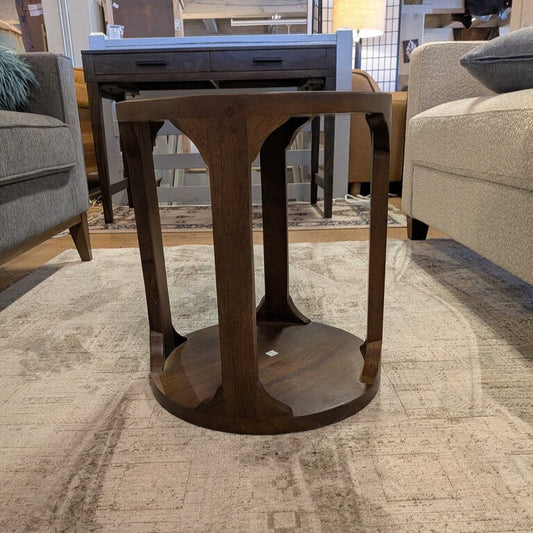 Wooden side table in a furniture store setting with chairs and other tables in the background.