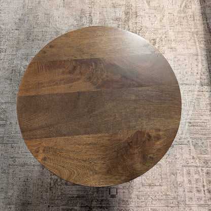 Round wooden table on a textured gray floor
