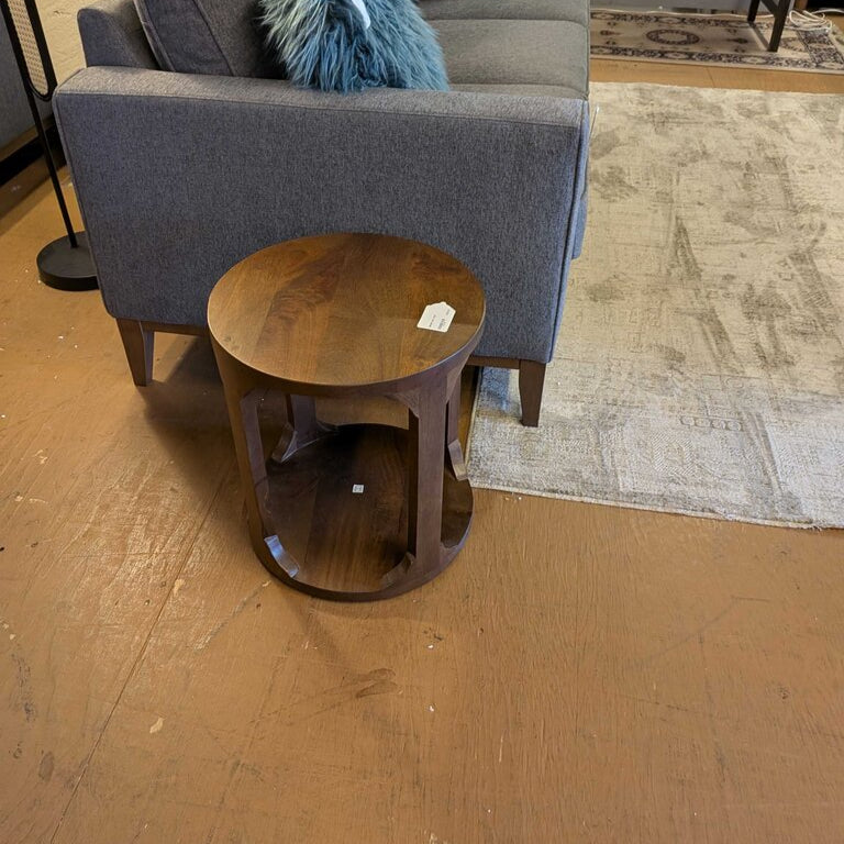 Gray sofa with blue pillows and a wooden side table on a wooden floor.