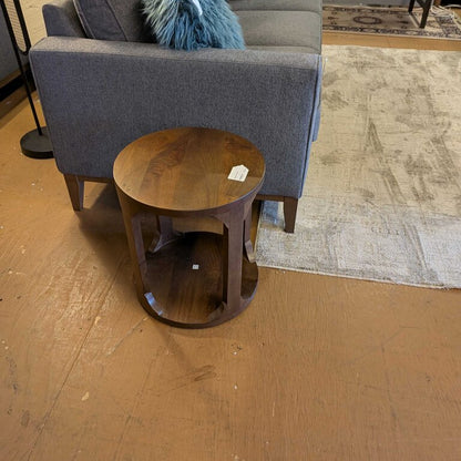 Gray sofa with blue pillows and a wooden side table on a wooden floor.