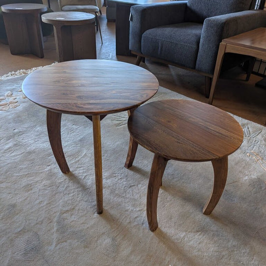 Wooden side tables on a textured floor with chairs and a couch in the background.