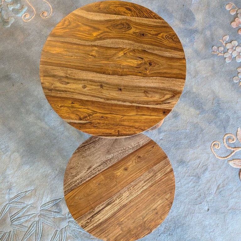 Round wooden table on a textured gray surface with floral patterns
