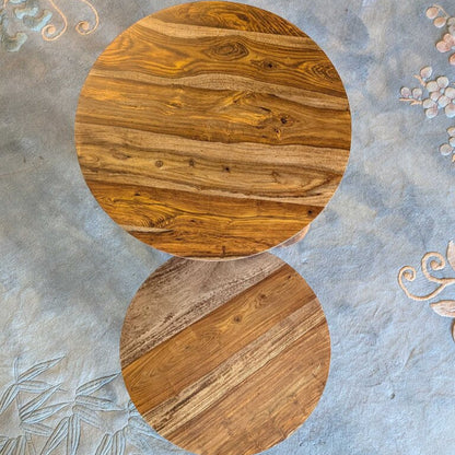 Round wooden table on a textured gray surface with floral patterns