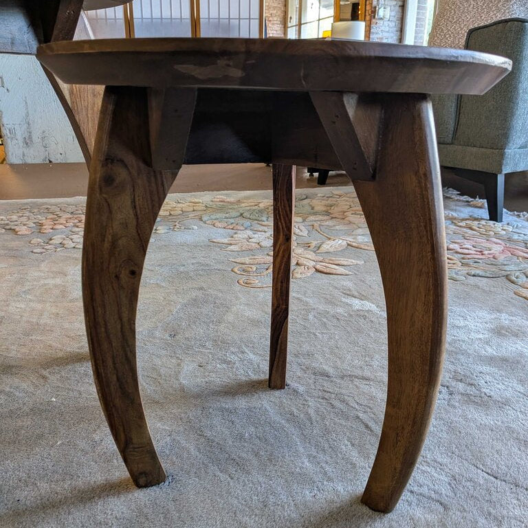 Wooden dining table with curved legs on a textured floor