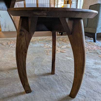 Wooden dining table with curved legs on a textured floor