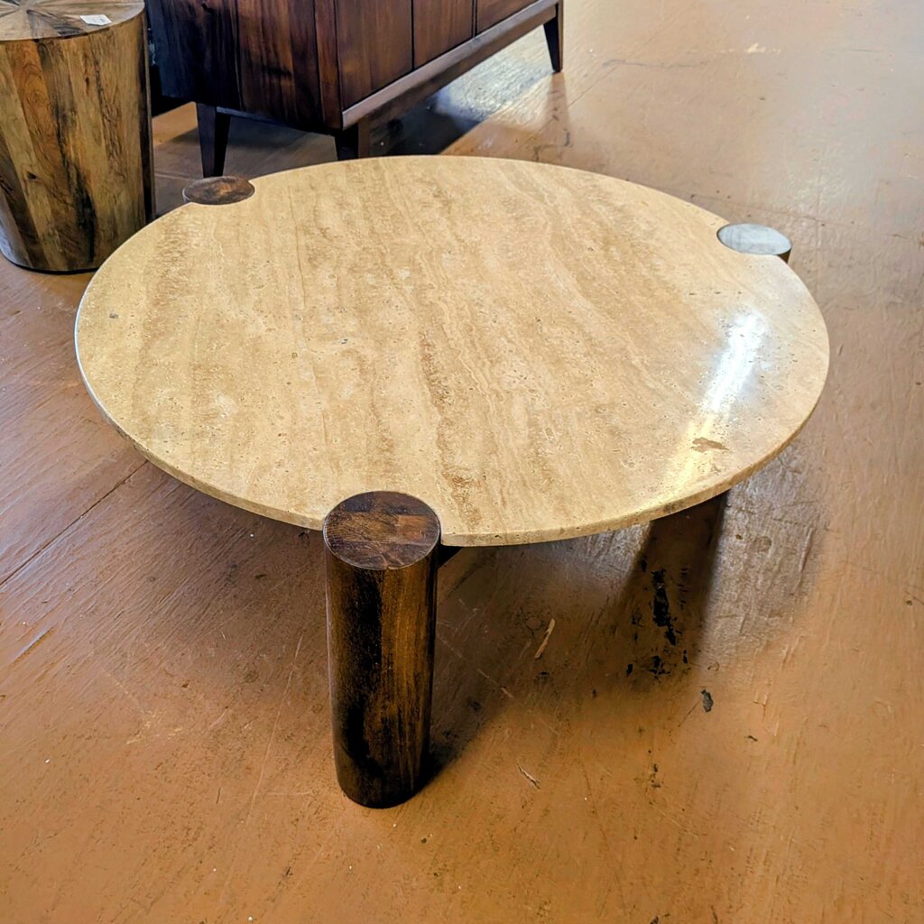 Round stone table with a wooden base on a wooden floor