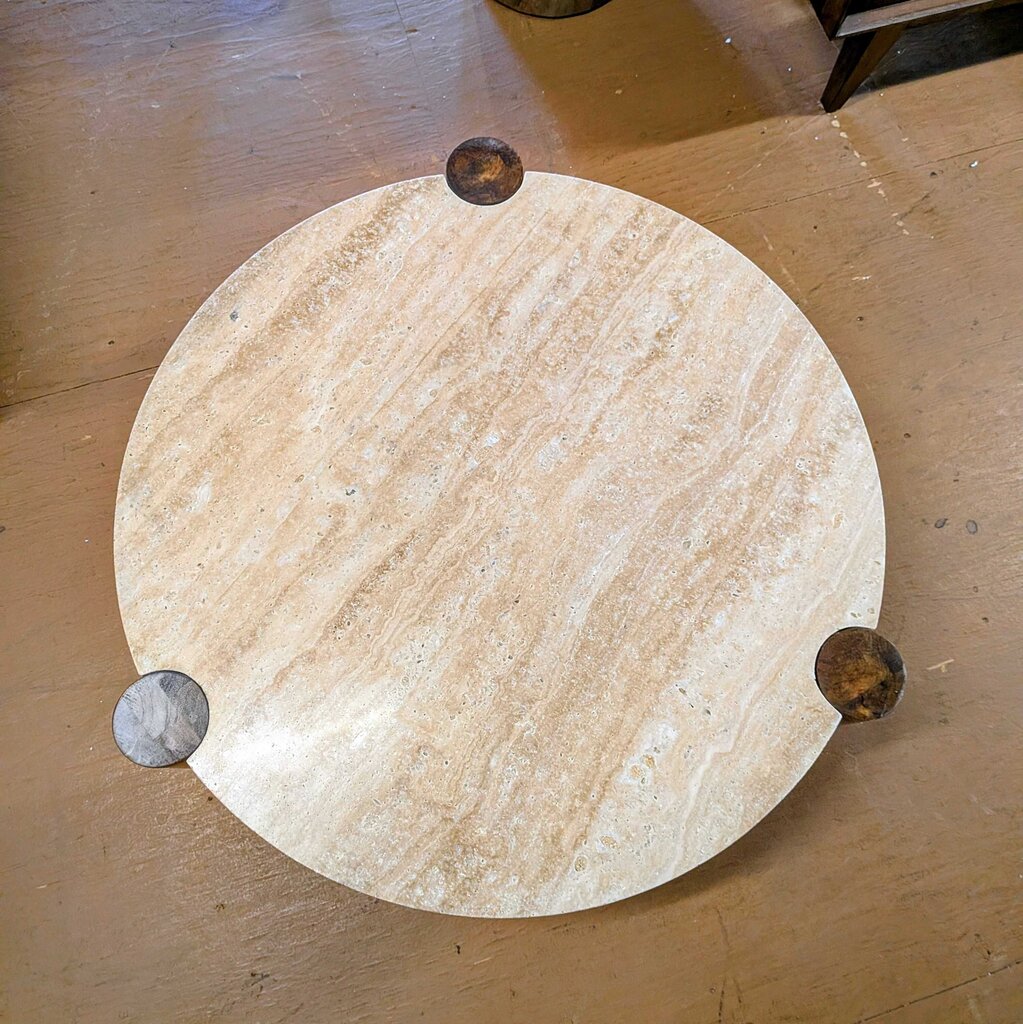 Round marble table with four legs on a wooden floor
