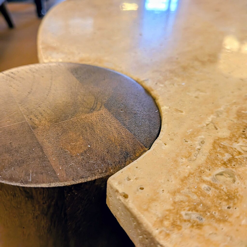 Close-up of a stone table with a metal bowl on top, blurred background