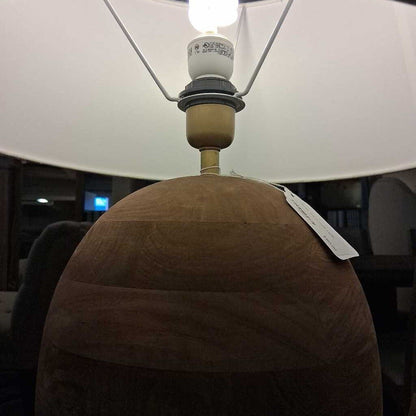 Close-up of a lamp with a brown base and white shade, blurred background