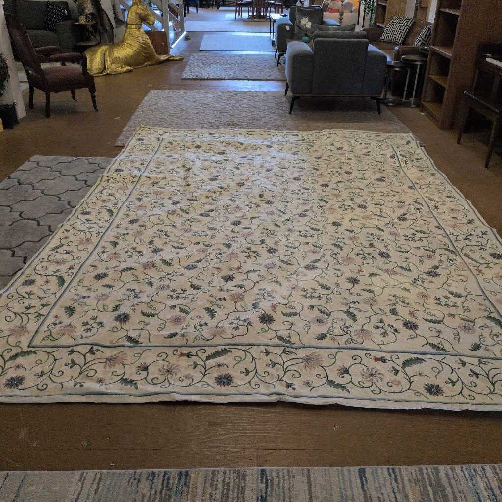 Large floral-patterned rug on a wooden floor with furniture in the background