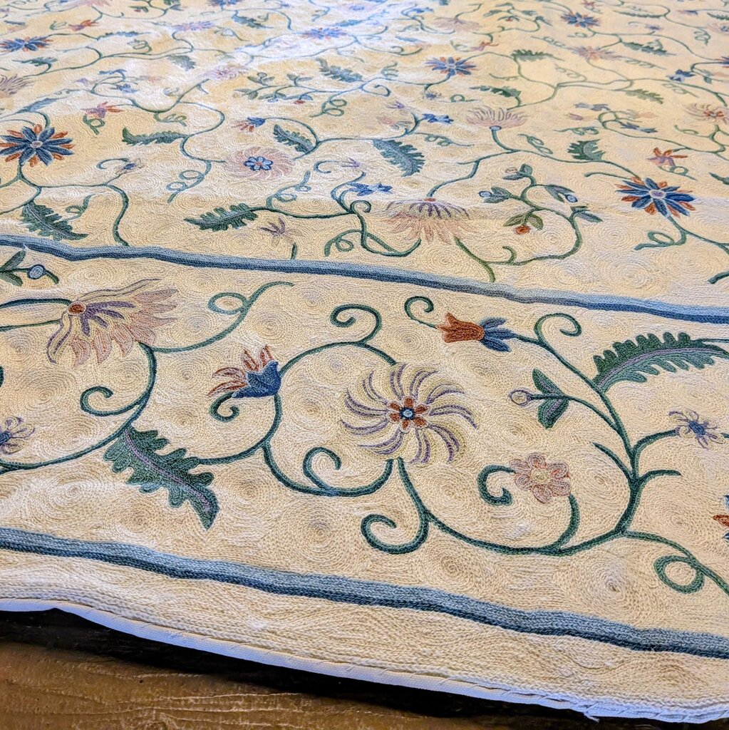 Close-up of a floral embroidered fabric with intricate patterns on a wooden surface.