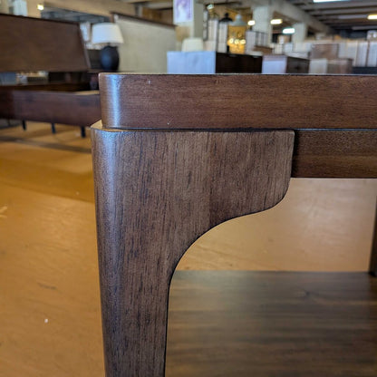 Close-up of a wooden table leg in an indoor setting with blurred furniture in the background