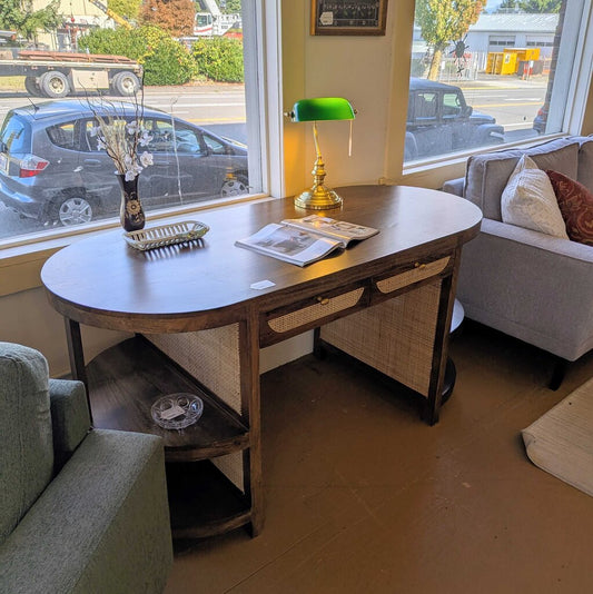 Wooden desk with a green lamp in a room with a view of a street.