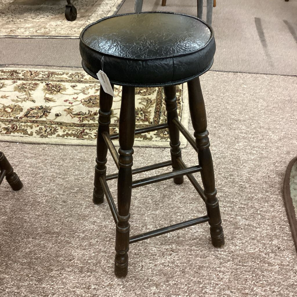 Black bar stool with leather seat on a carpeted floor
