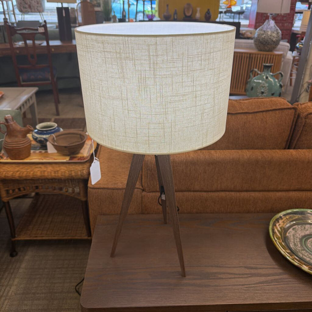 Table lamp with a textured beige shade on a wooden base in a room setting.