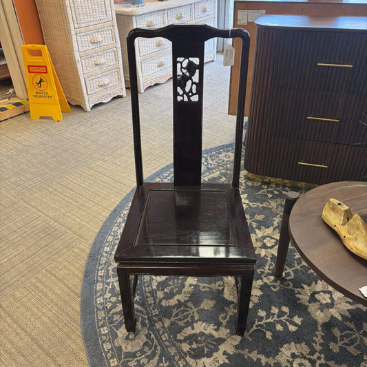 Dark wooden chair with decorative backrest on a patterned rug