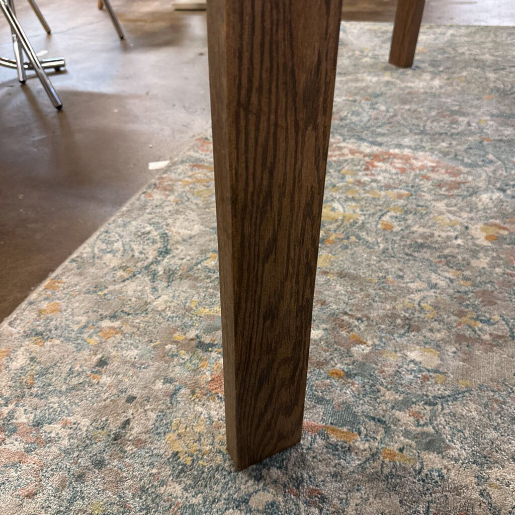 Wooden leg of a table on a patterned carpet