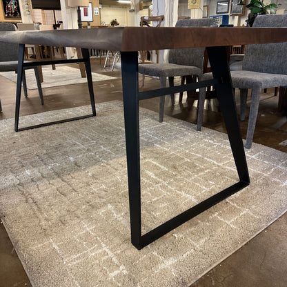 Dining table with black metal legs on a textured rug in a showroom setting