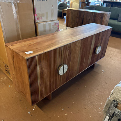 Wooden cabinet with circular handles on a floor with cardboard boxes in the background