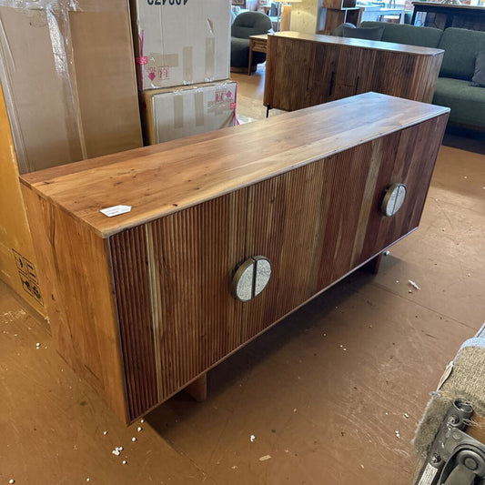 Wooden cabinet with circular handles on a floor with cardboard boxes in the background