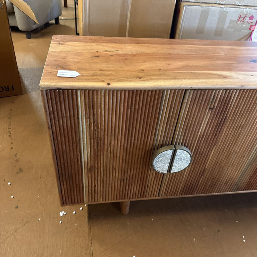 Wooden cabinet with slatted design and circular handle on a wooden floor.