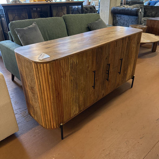 Wooden sideboard with ribbed design in a furniture store setting