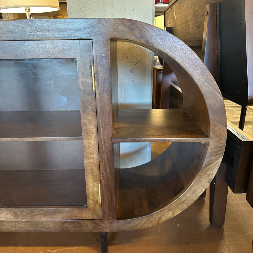 Wooden circular shelf with glass panels in a room setting