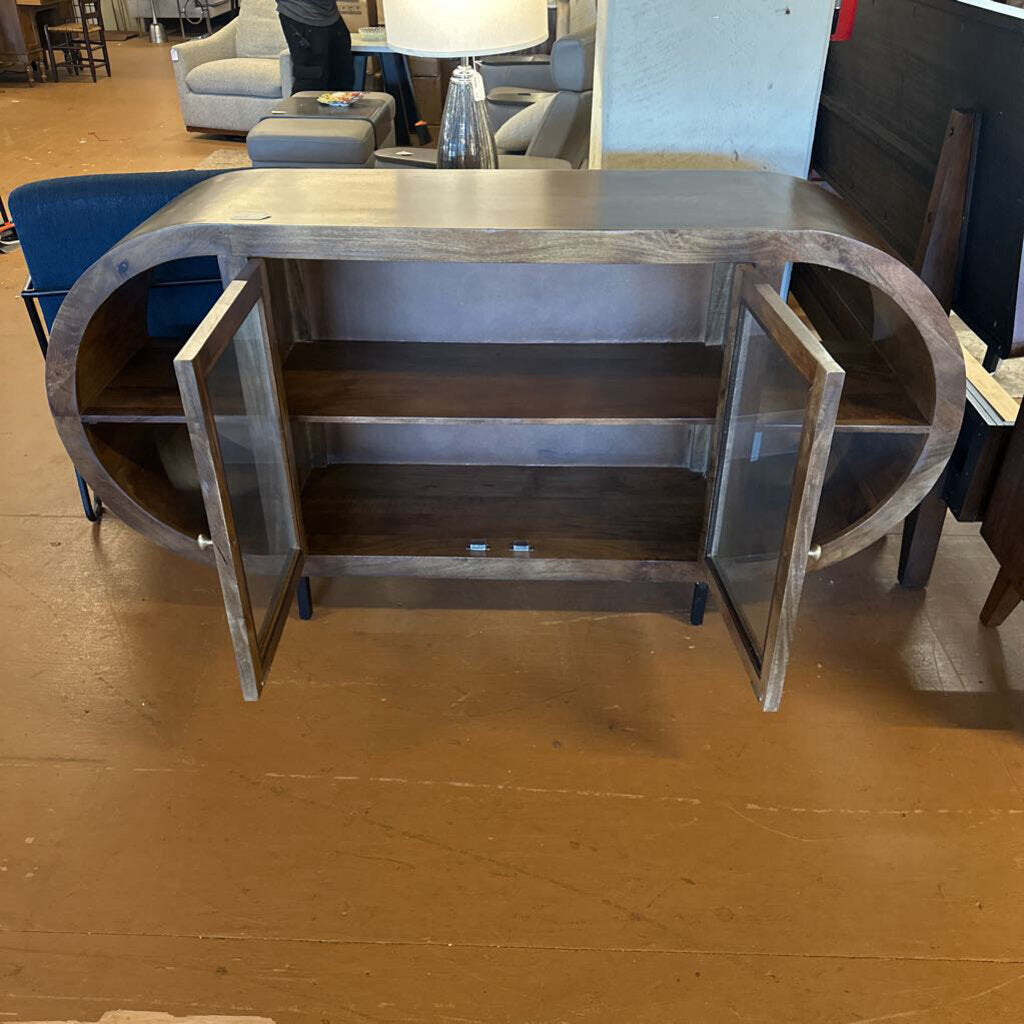 Wooden console table with glass doors in a showroom setting