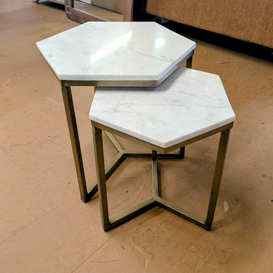 Hexagonal marble top tables with brass frames on a wooden floor.