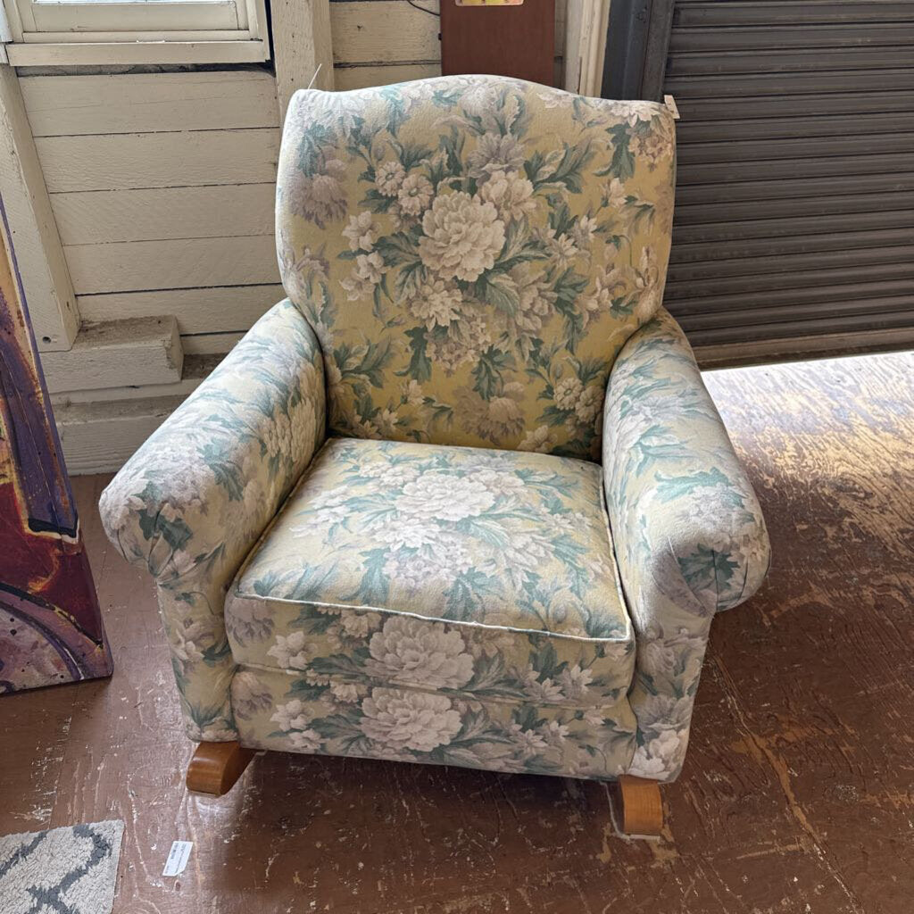 Floral-patterned armchair in a room with wooden floor and white walls.