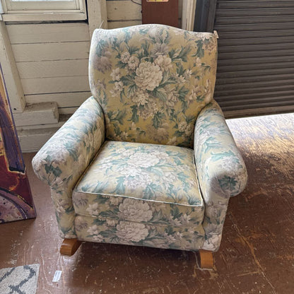 Floral-patterned armchair in a room with wooden floor and white walls.