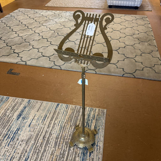 Decorative metal stand with lyre design on a wooden floor.