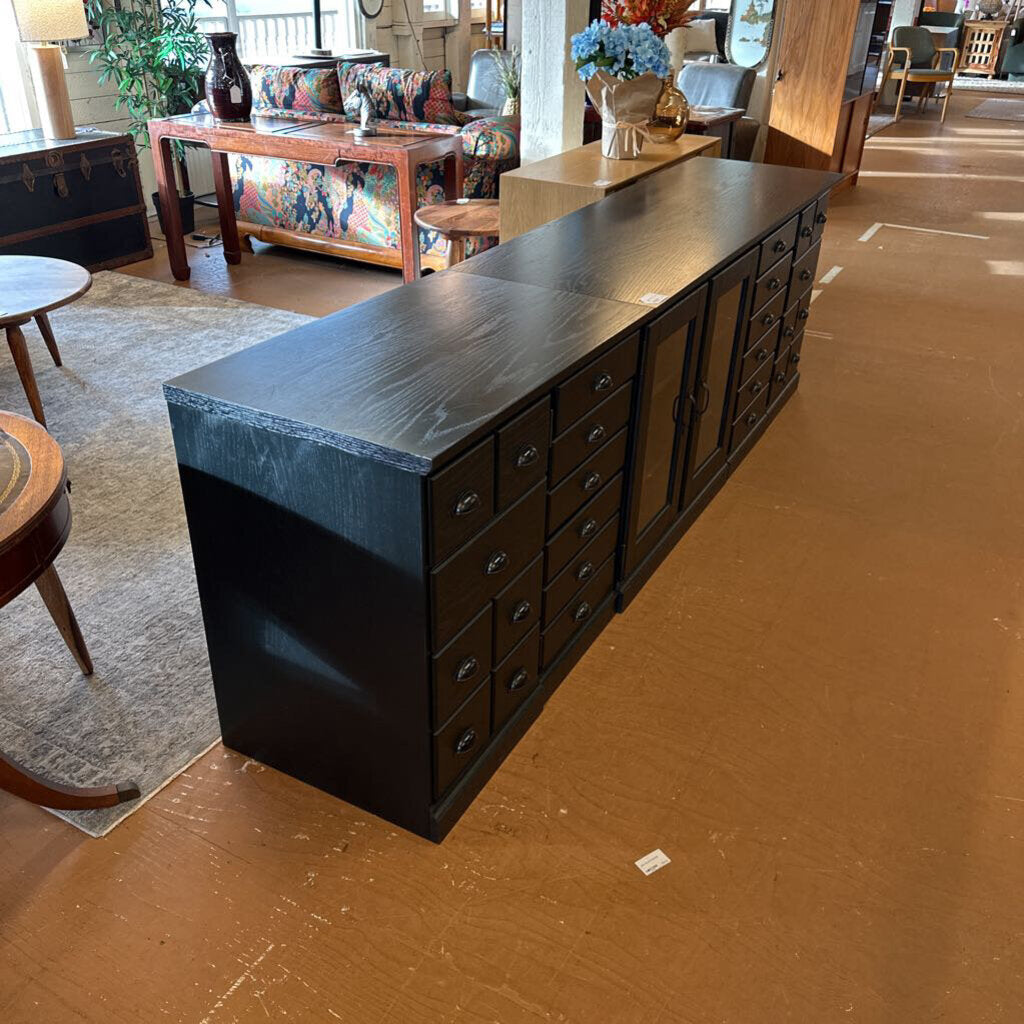 Long dark wooden dresser with multiple drawers in a room setting.