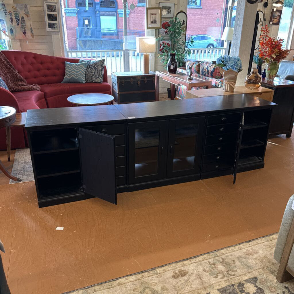 Black entertainment console in a living room setting with furniture and decor.