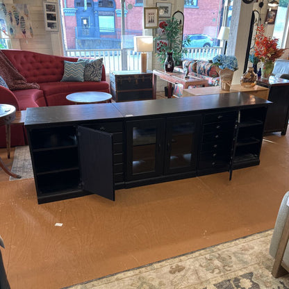 Black entertainment console in a living room setting with furniture and decor.