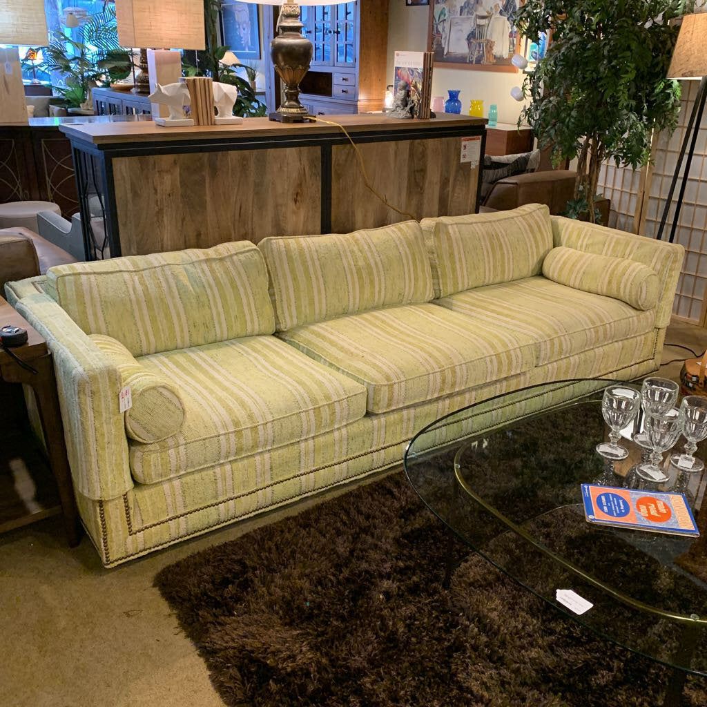 Green striped sofa in a room with a glass coffee table and decorative items.