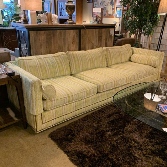 Green striped sofa in a room with a glass coffee table and decorative items.