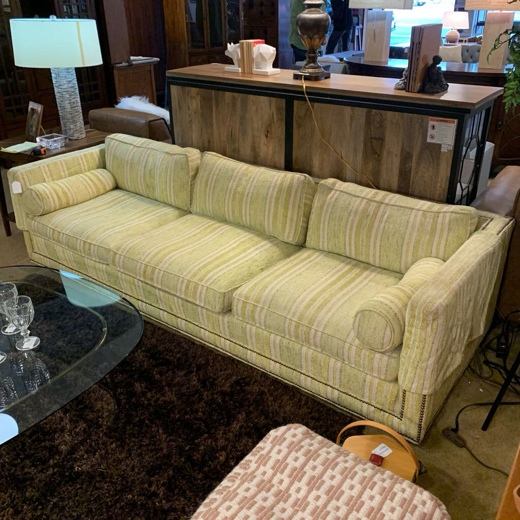 Striped green sofa in a room with a coffee table and decorative items.