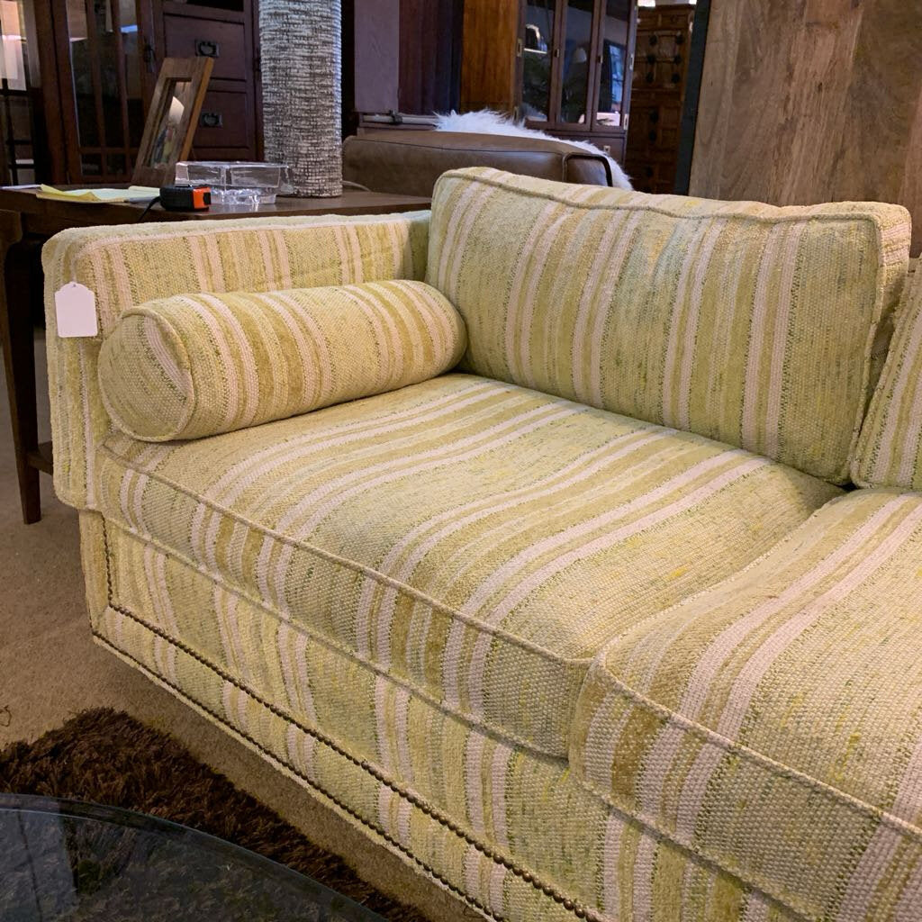 Green striped sofa in a room with furniture and decor.