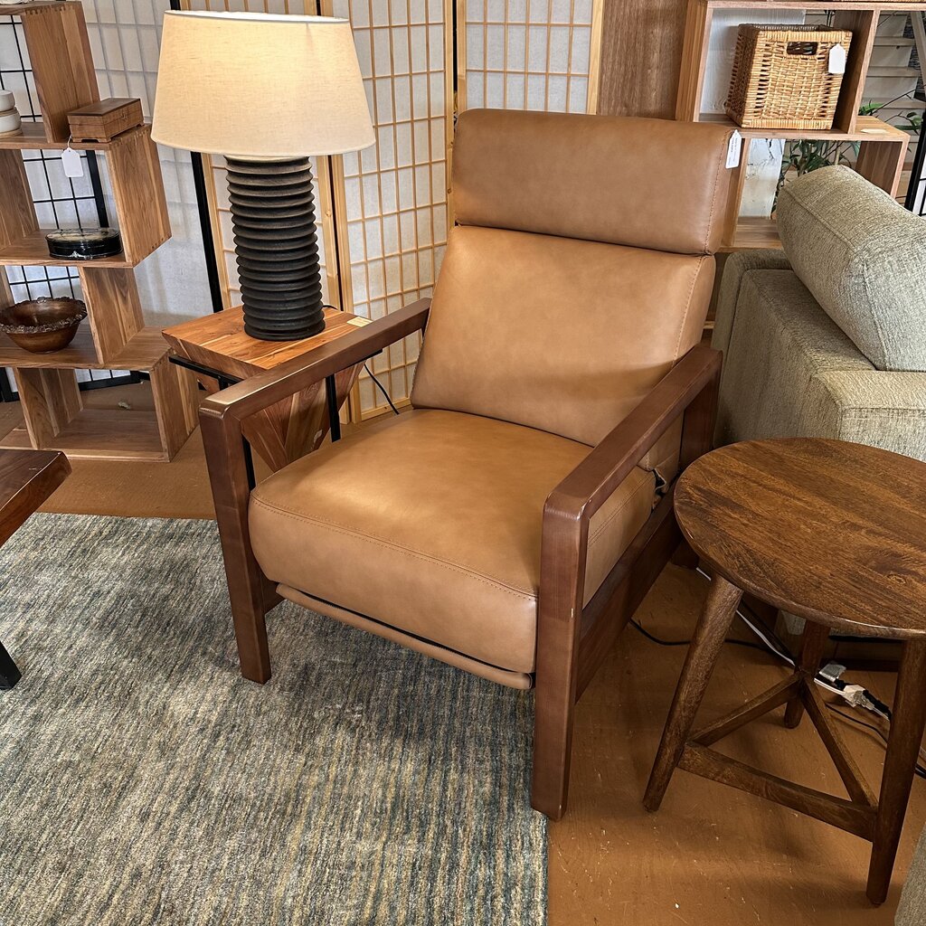 Brown leather armchair in a room with wooden furniture and decor.